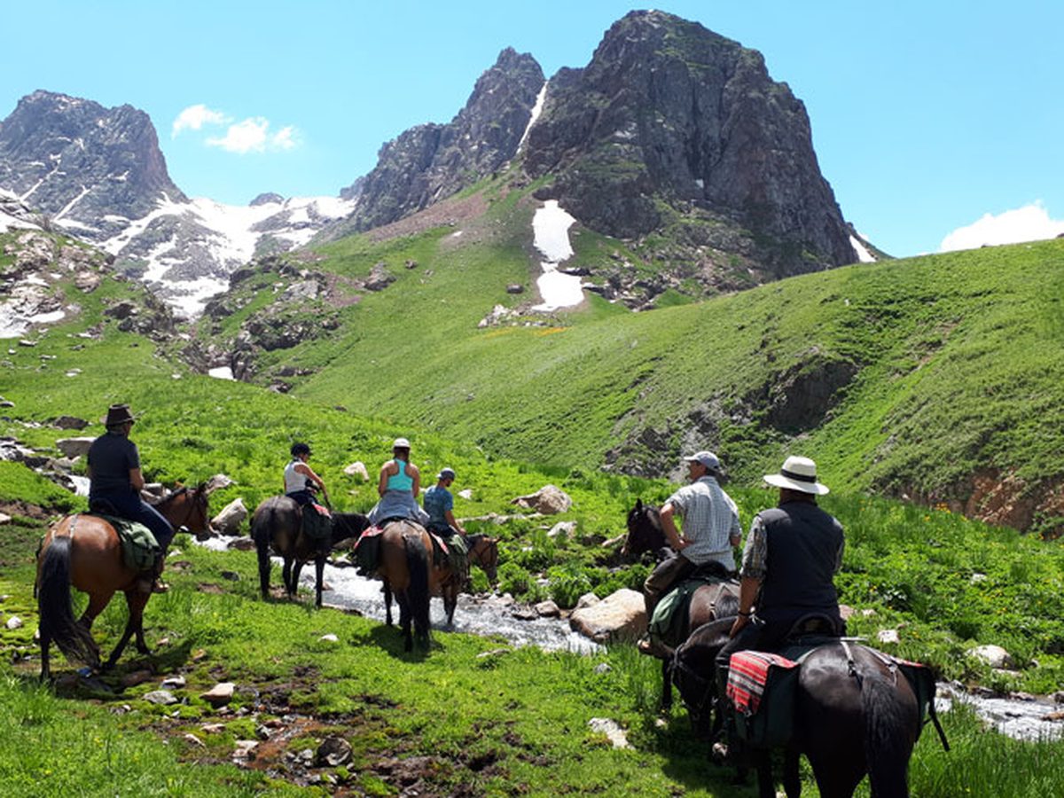 Groupe de cavaliers en randonnée à cheval dans les montagnes du Kirghizistan, vallée de Suusamyr