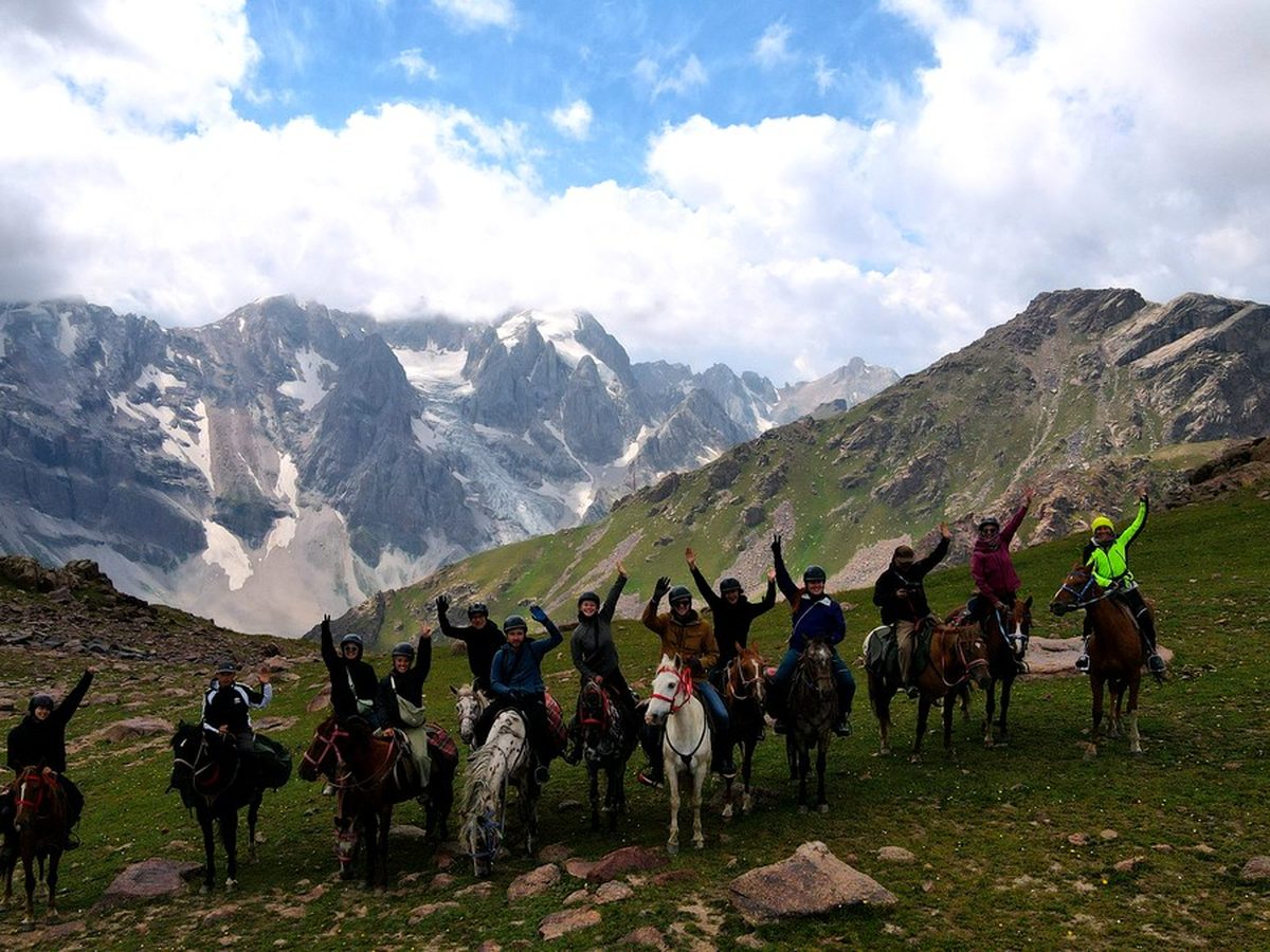 Groupe de cavaliers sur les hauts pâturages du Kirghizistan avec glacier Muz Tor en arrière-plan